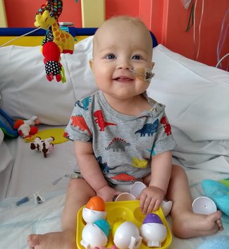 A little boy smiling on a bed