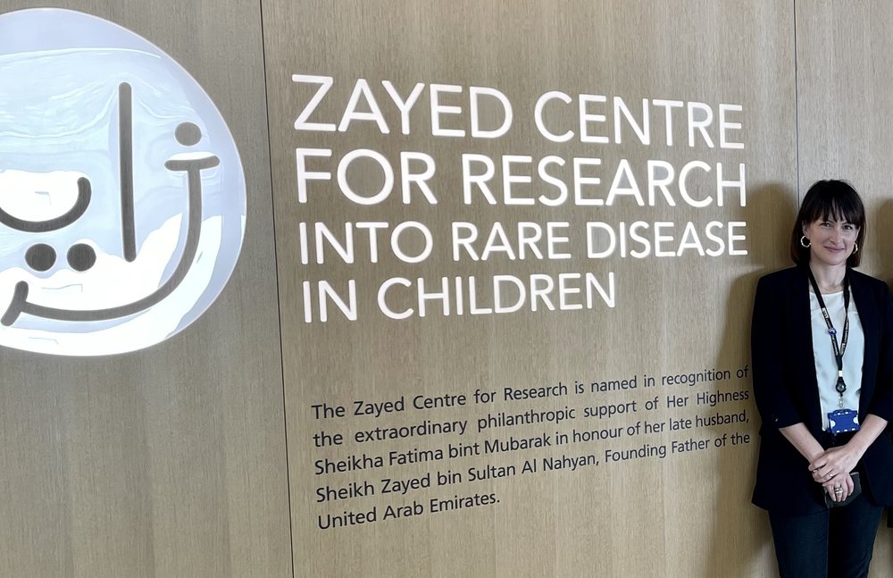Dr Alessia Cavazza standing next to the entrance sign for the Zayed Centre for Research into Rare Disease in Children