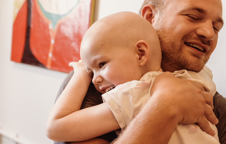 A child smiling and hugging her dad.