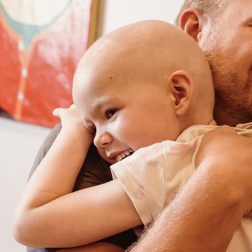 A child smiling and hugging her dad.