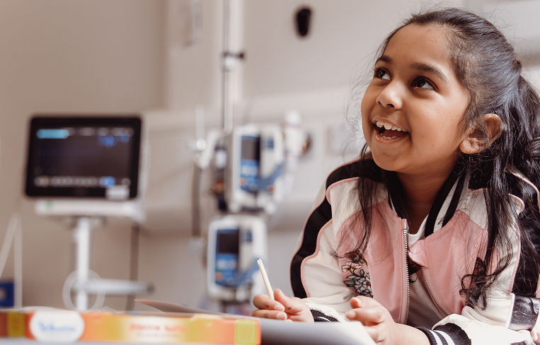 Little girl sitting on hospital bed smiling