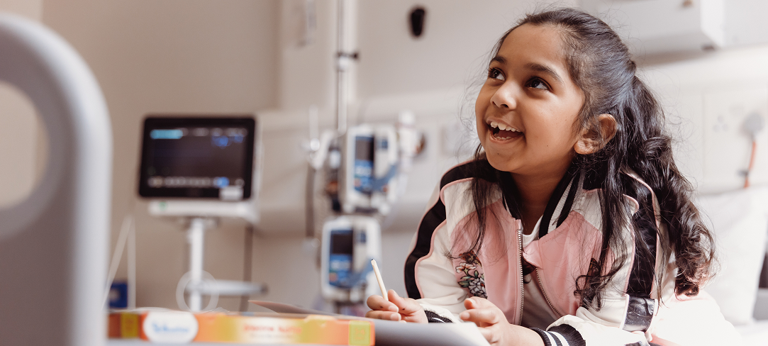 Little girl sitting on hospital bed smiling