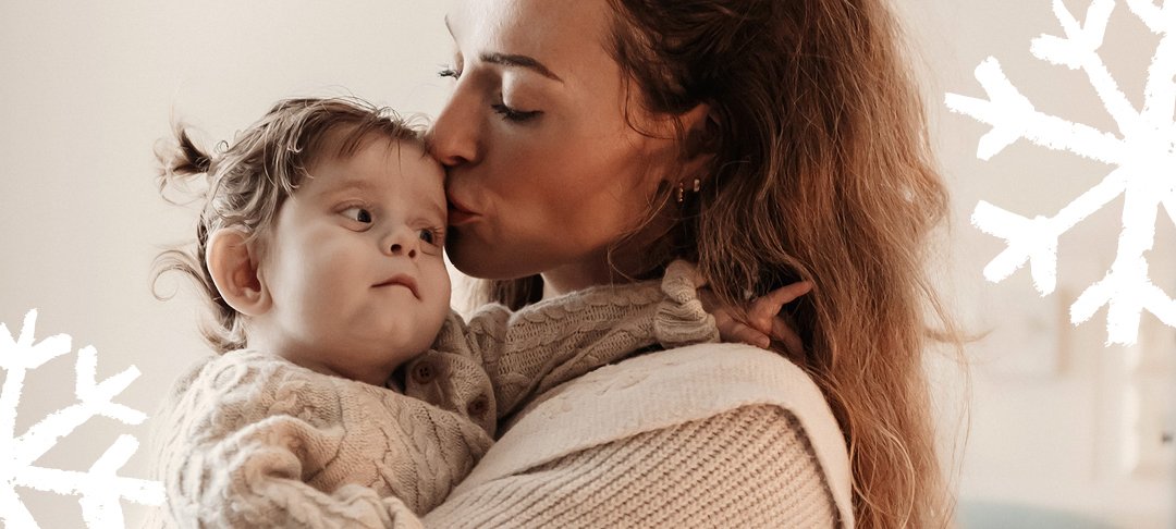 A woman holds her little girl. Doodles of snowflakes overlay the image.