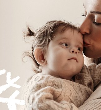 A woman holds her little girl. Doodles of snowflakes overlay the image.