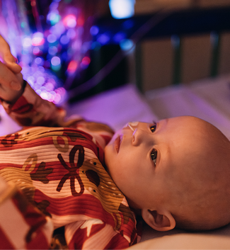 Baby in bed at GOSH, wearing Christmas outfit