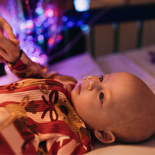 Baby in bed at GOSH. She is wearing a Christmas outfit and has an NG feeding tube.