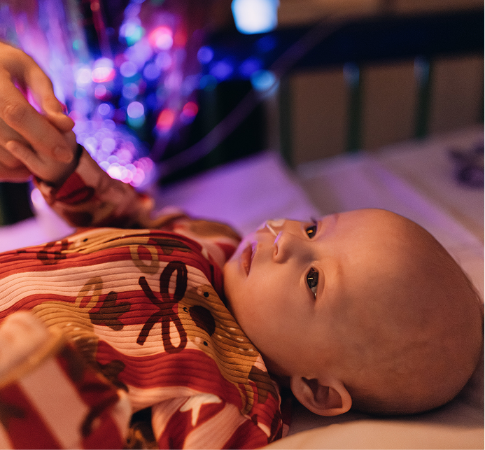 Baby in bed at GOSH. She is wearing a Christmas outfit and has an NG feeding tube.