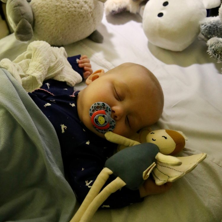 Emmie in her cot at GOSH. Cuddly toys can be seen in the background.