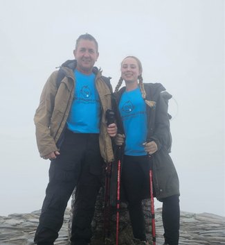 A man and woman outside on a hike wearing GOSH Charity tshirts.