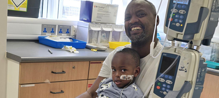Little boy sitting on his dad's lap in hospital