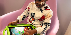 A little boy wearing Spiderman pyjamas playing on a tablet in hospital