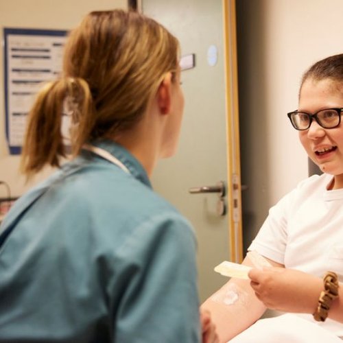 nurse sits with teenage girl in hospital room