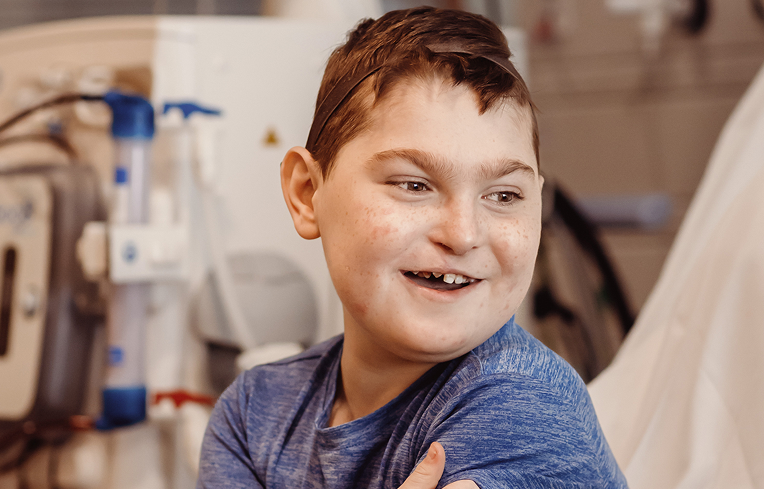 Boy sitting on hospital bed, smiling