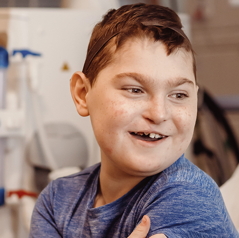 Boy sitting on hospital bed, smiling