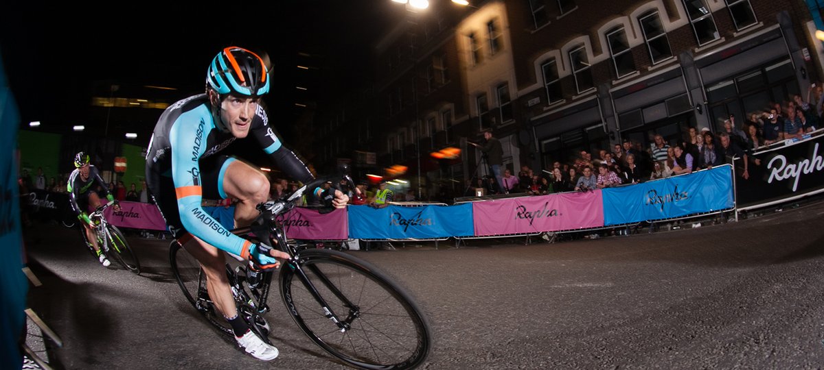 Professional cyclist on bike mid-race. People cheer him on.