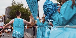 TeamGOSH runner high-fiving volunteers at the GOSH Charity cheer station, as they run past.