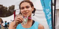TeamGOSH runner smiling at the camera, holding their medal up to show the camera