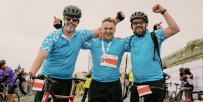 Three TeamGOSH Cyclists smiling at the camera at the finish line of the London to Brighton Cycle.