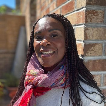 A woman with a colourful scarf is smiling at the camera