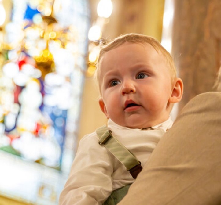A little boy pictured inside a chapel. He is looking into the distance.
