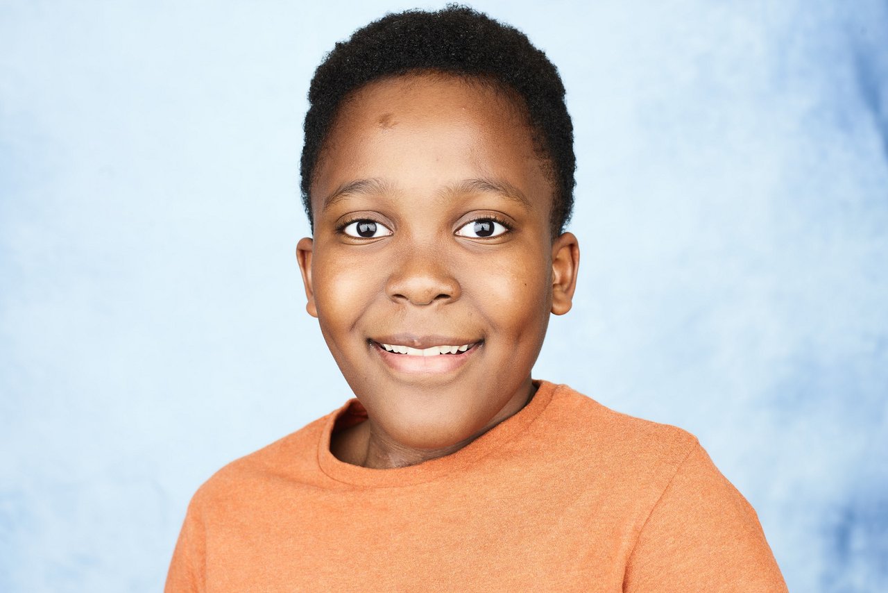 Portrait of GOSH patient Oba by photographer Rankin. Oba wears an orange top and is smiling to camera.