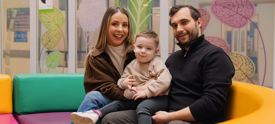 A smiling little boy sitting on his parent's lap