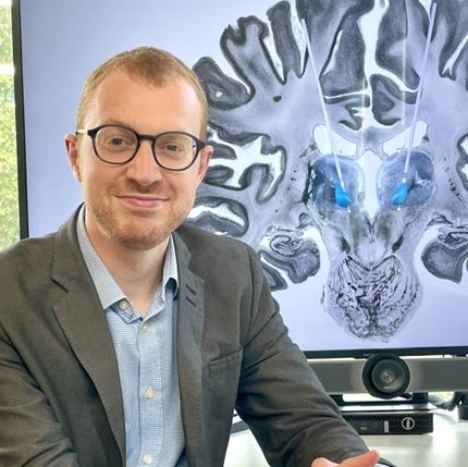 A researcher sat in front of a screen with a brain scan on it