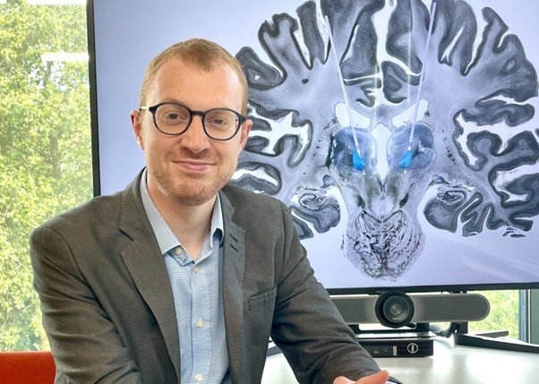 A researcher sat in front of a screen with a brain scan on it
