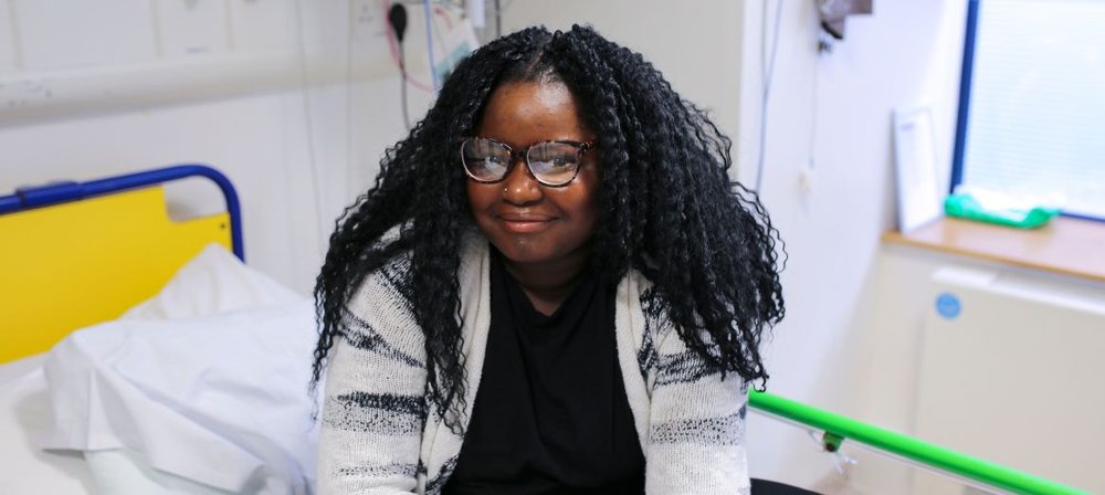 Rue sitting on her bed at GOSH, smiling and looking to camera.