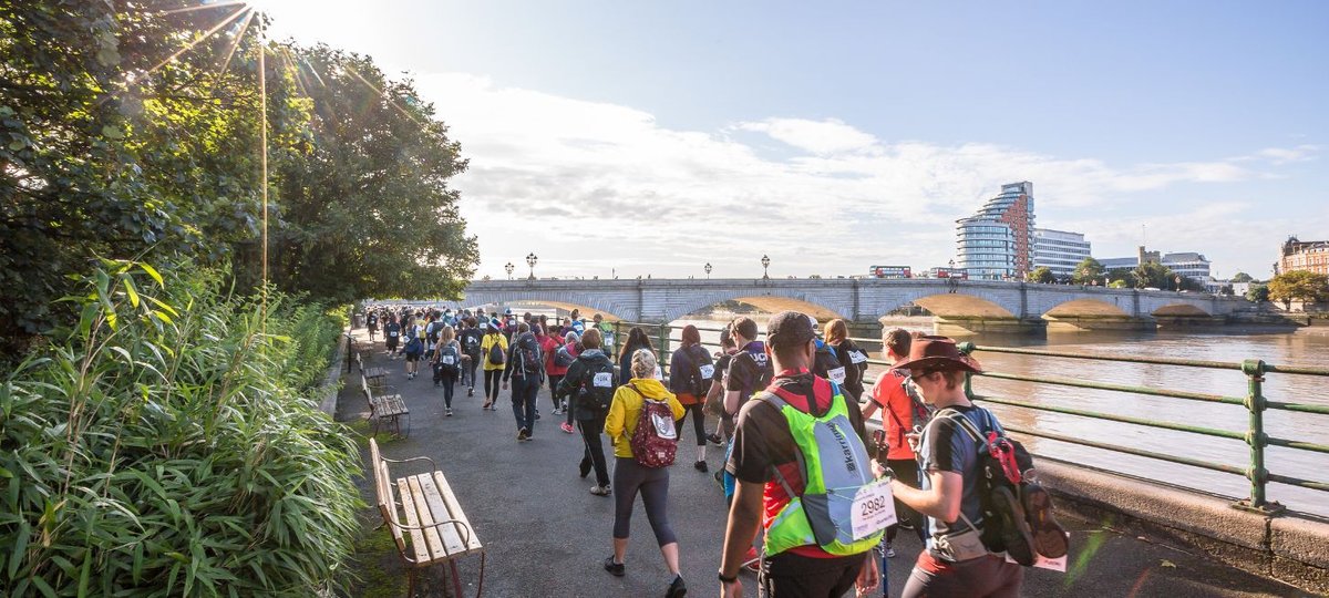 Participants walking along a path with walking sticks and in hiking gear with london views