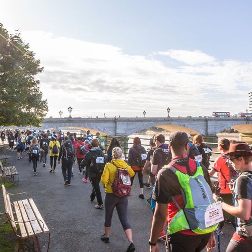 Participants walking along a path with walking sticks and in hiking gear with london views