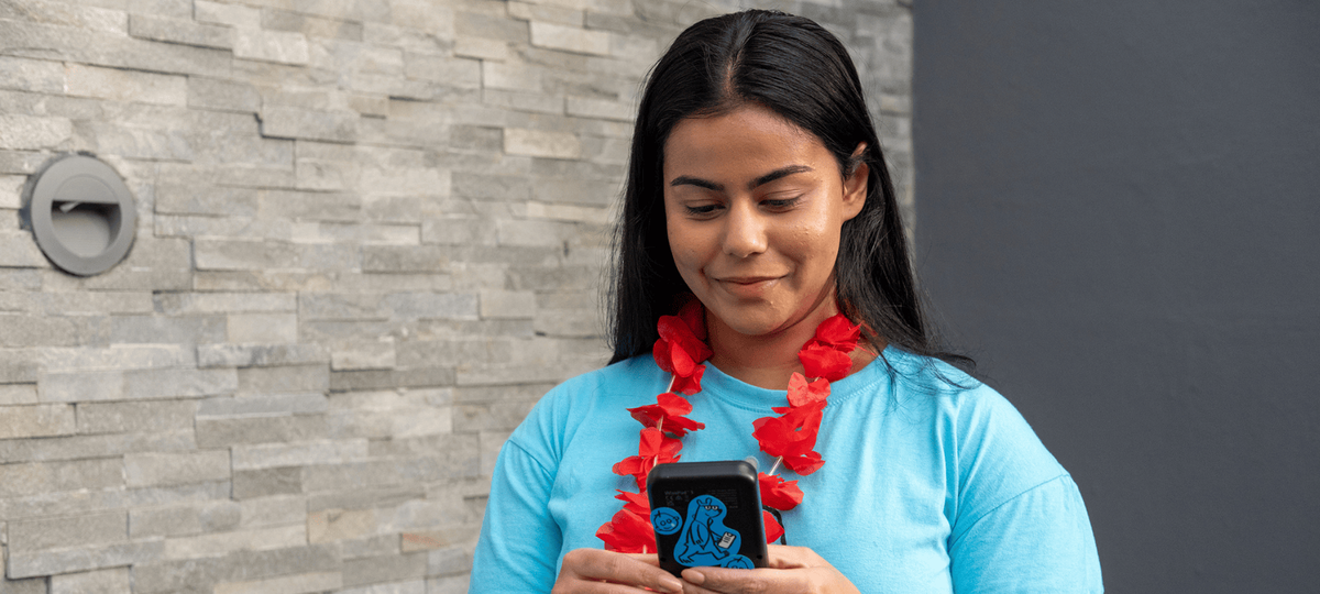 A volunteer in a blue tshirt holds a small, black donation device