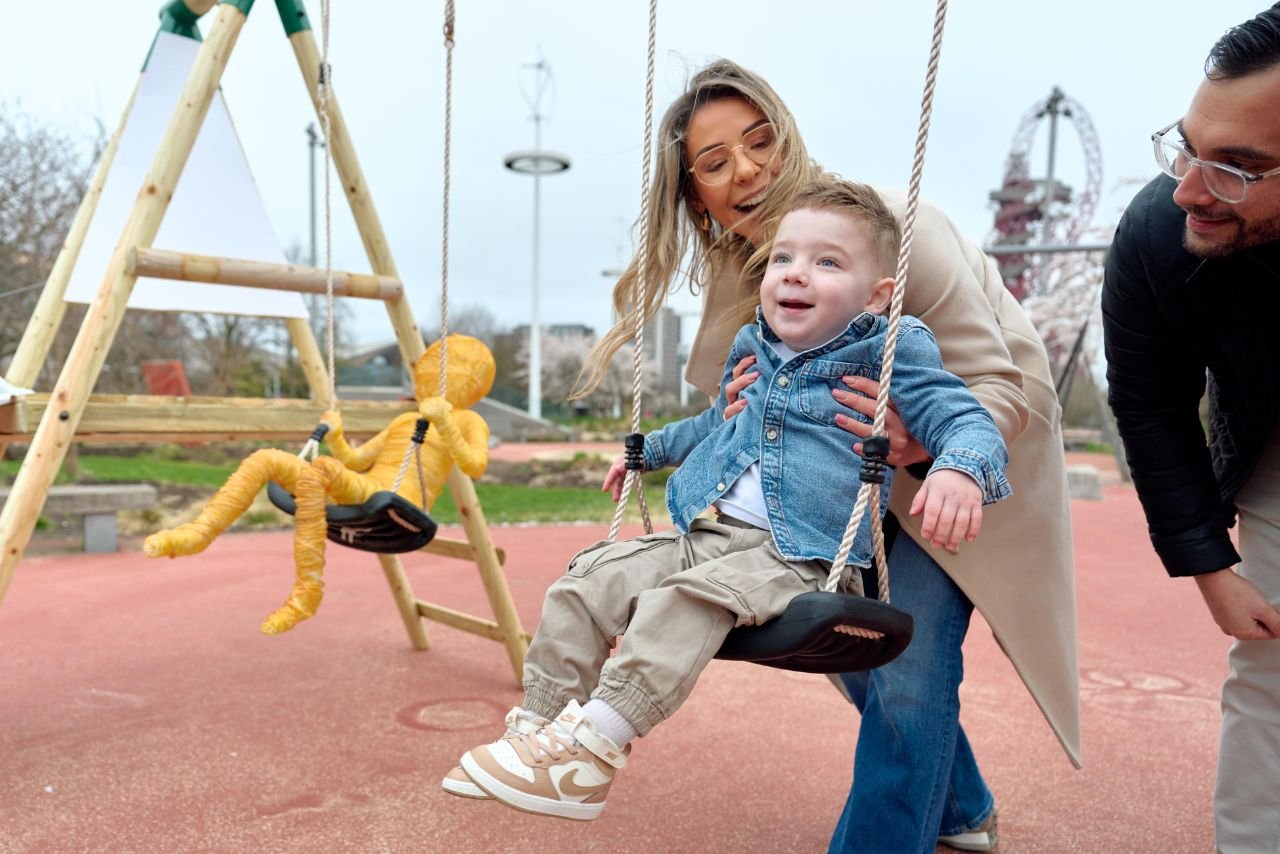Little boy next to sculpture created using replica chemotherapy wires, both on swing