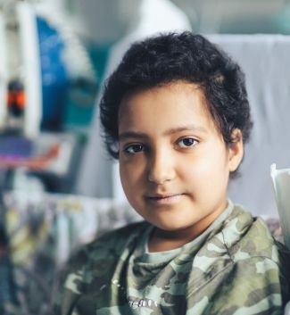 Photo of GOSH patient. She is sitting in a hospital bed and looking at the camera