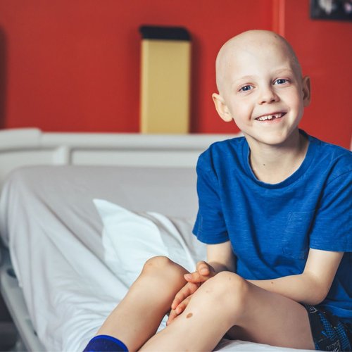 Little boy sitting on hospital bed, smiling to camera