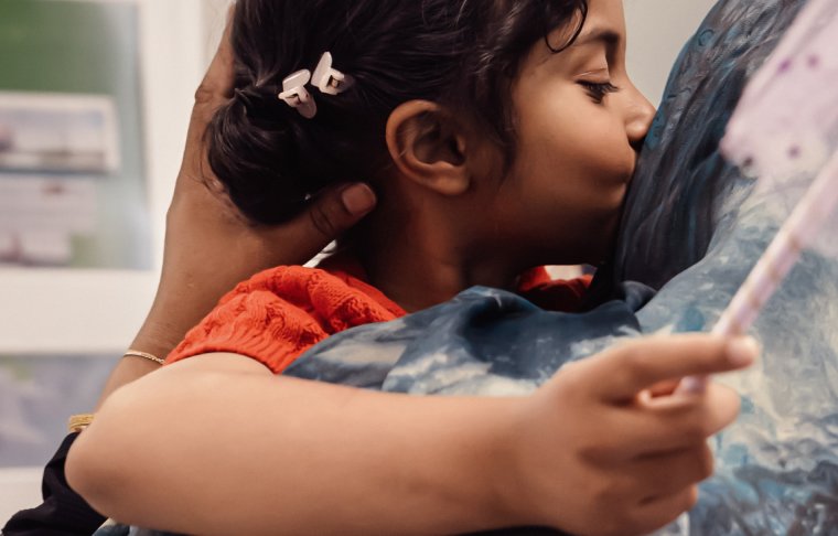 Little girl holding wand and kissing her mum on cheek