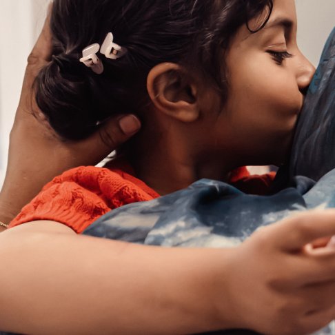 Little girl holding wand and kissing her mum on cheek