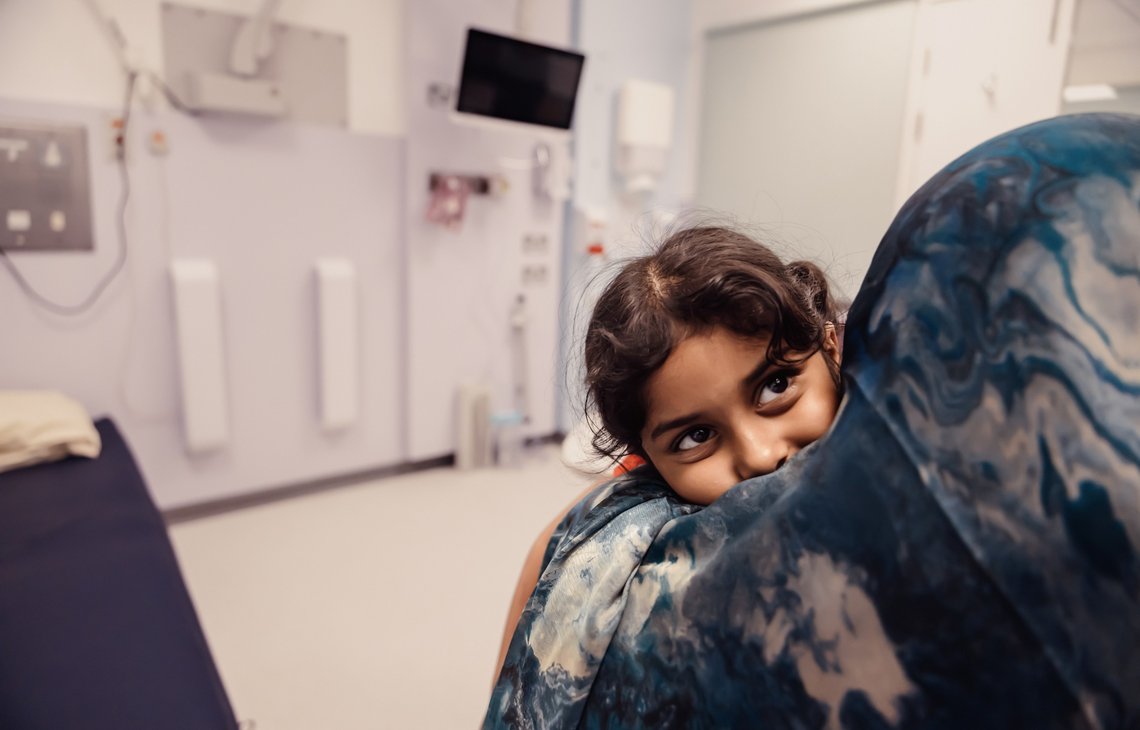 A little girl hugs her mum while in hospital room