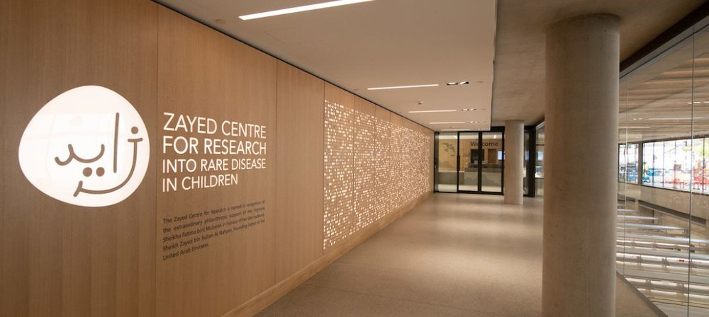 Photo taken inside the ZCR. Logo on the wall alongside sign reading Zayed Centre for Research into Rare Disease in Children