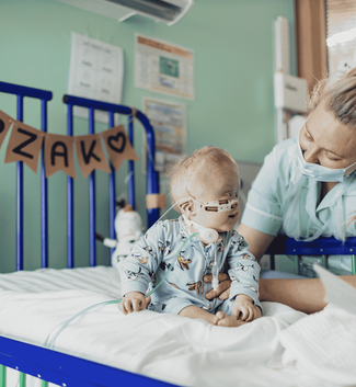 Zak in hospital with a sign across his bed with his name.