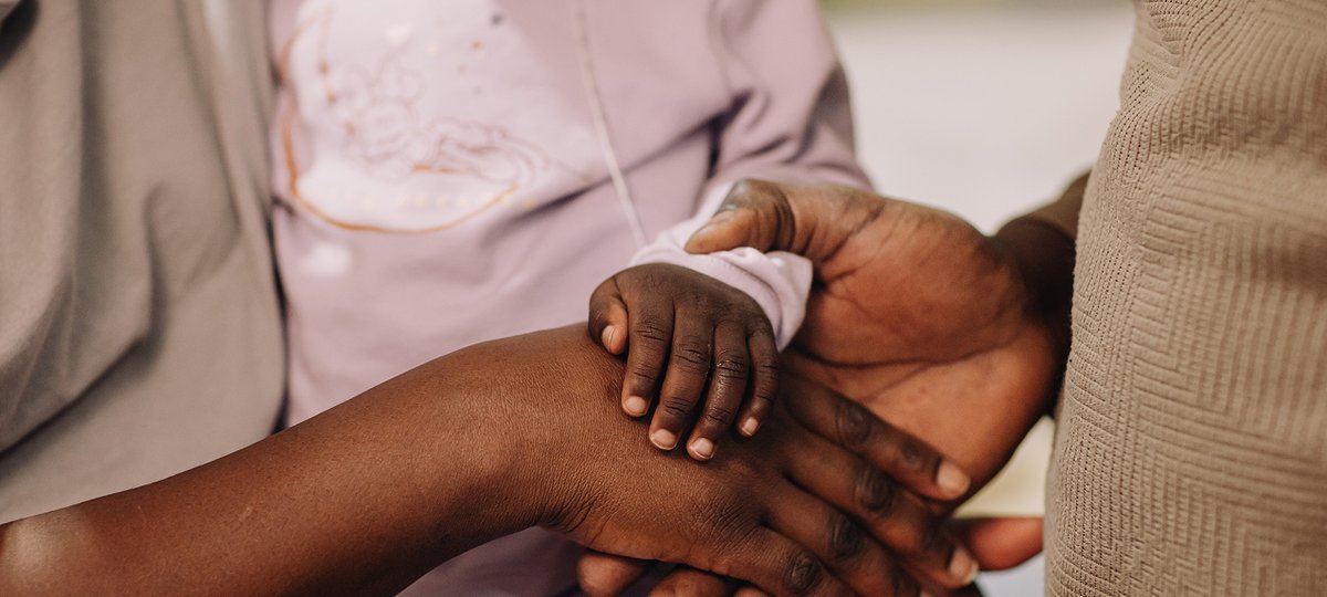 A close up of parents hands holding their child's hands