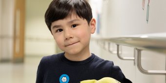 Little boy with a GOSH Charity sticker on his top smiling to camera