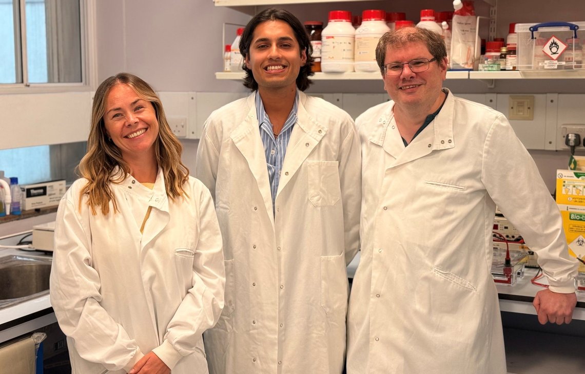 The research team behind the breakthrough stand in a lab, smiling to camera.