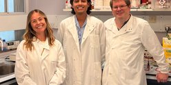 The research team behind the breakthrough stand in a lab, smiling to camera.