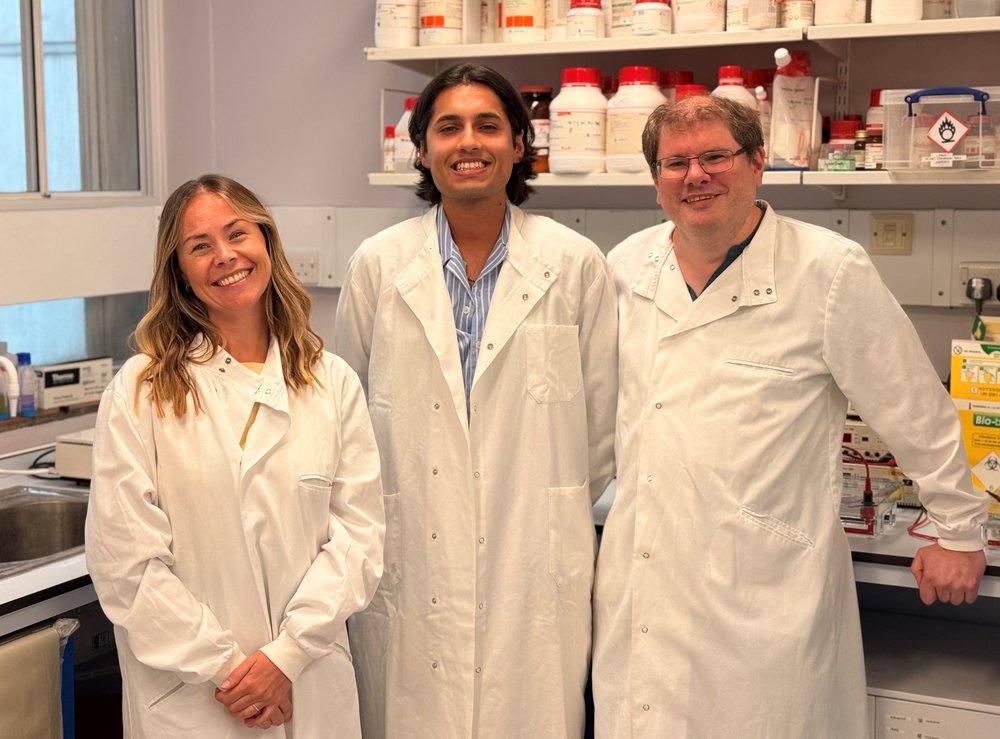 The research team behind the breakthrough stand in a lab, smiling to camera.