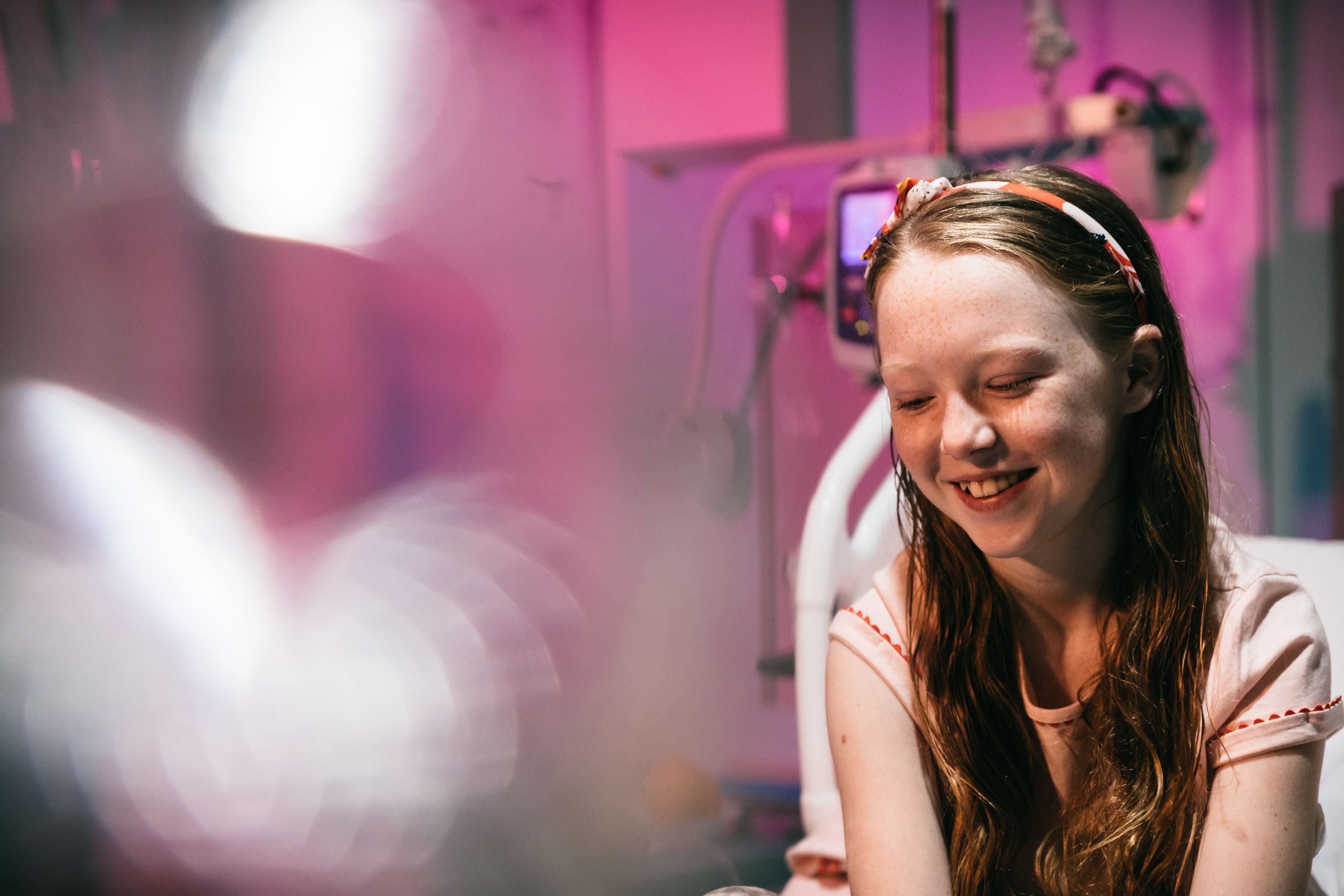 A happy looking young girl in a hospital bed.