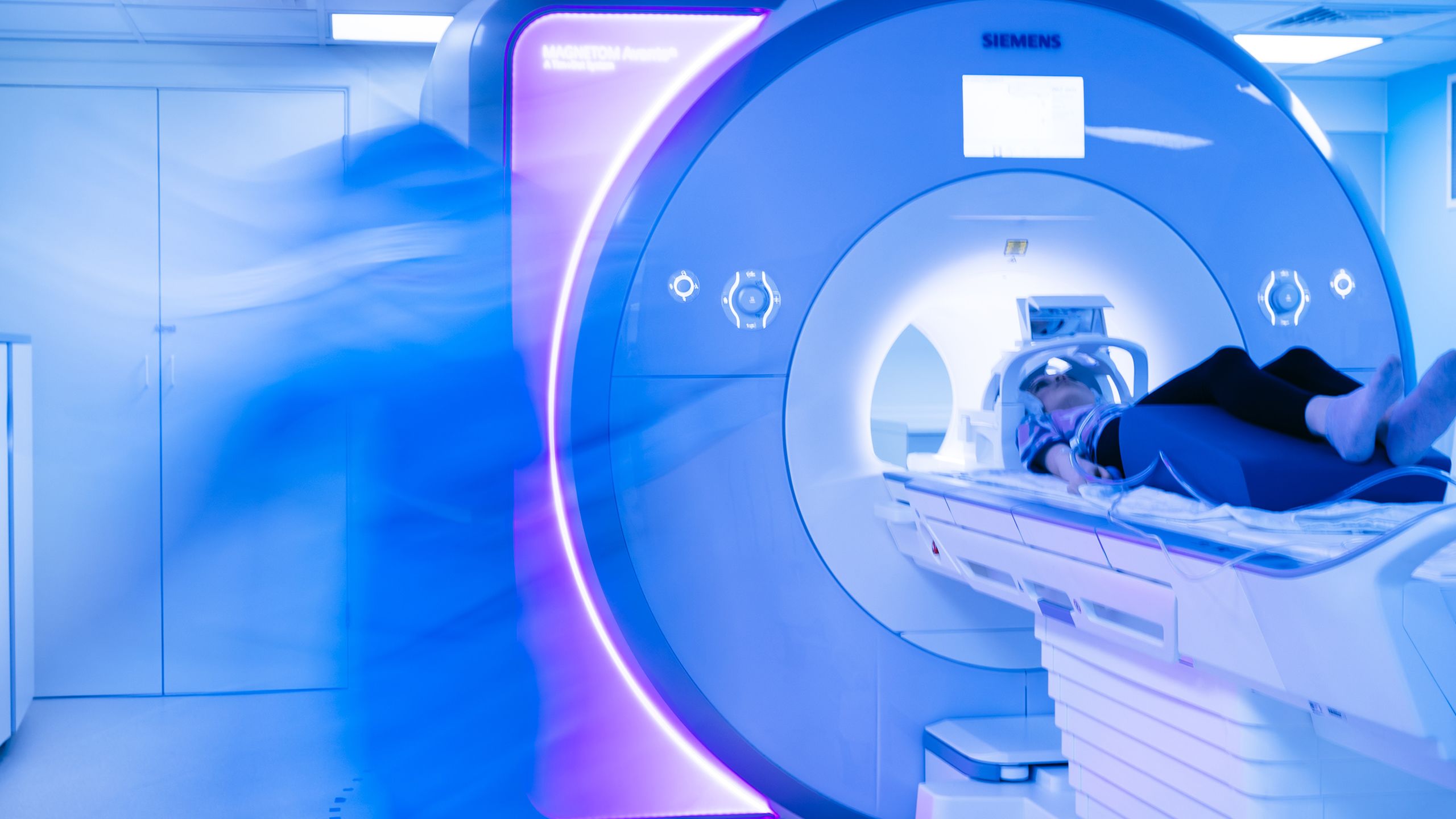 A girl lying inside a glowing blue MRI scanner.