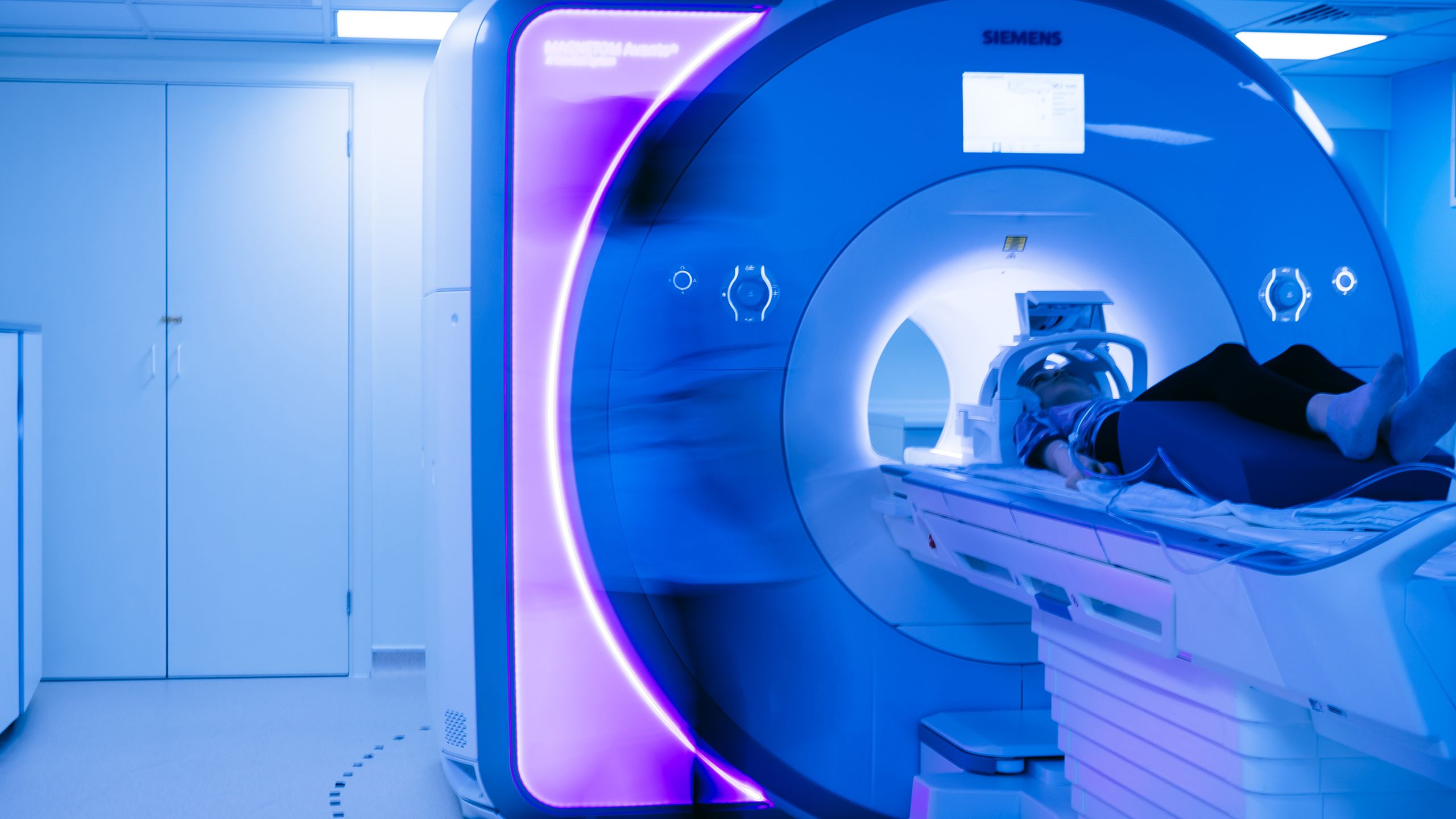 A girl lying inside a glowing blue MRI scanner.