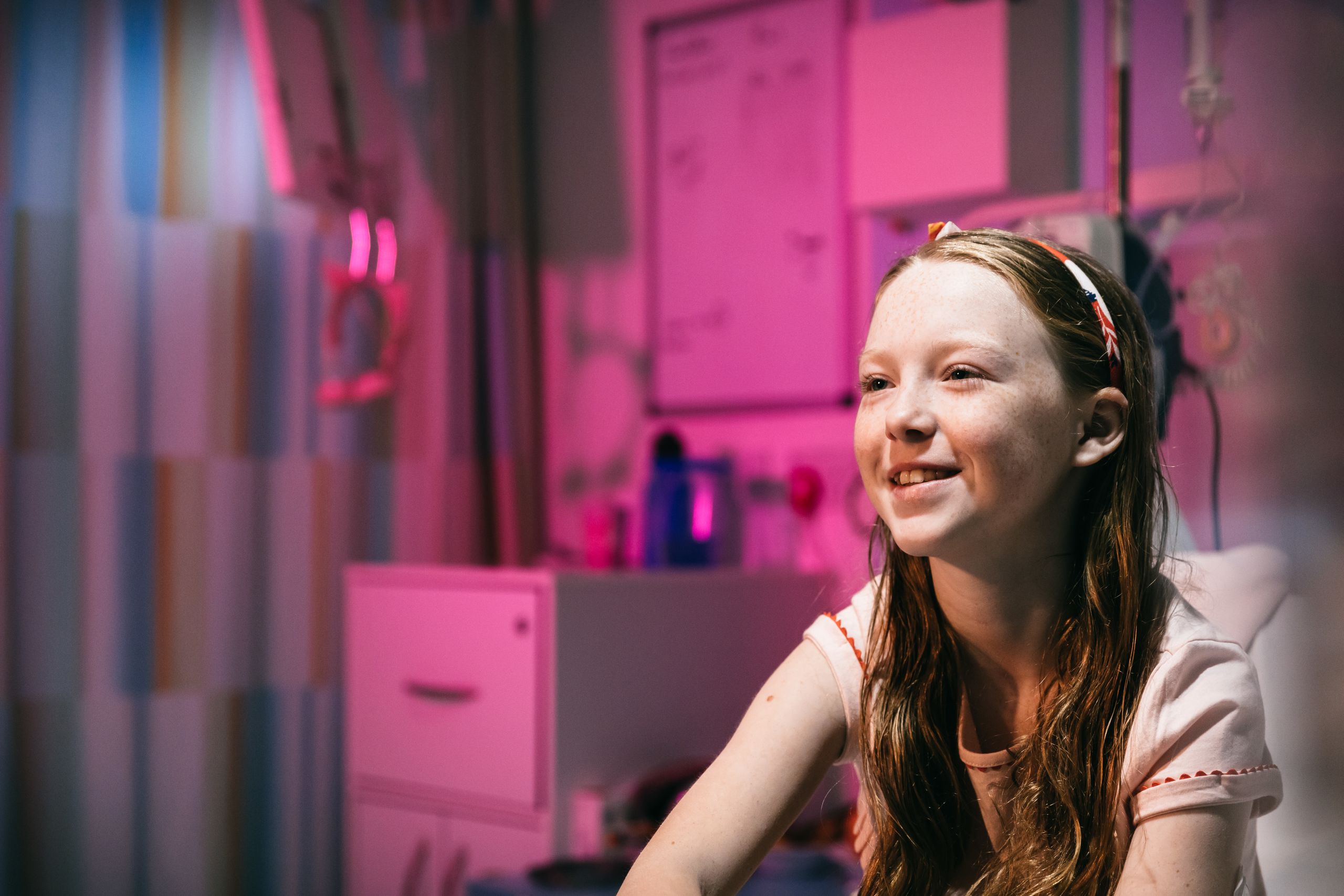 A happy looking young girl in a hospital bed.