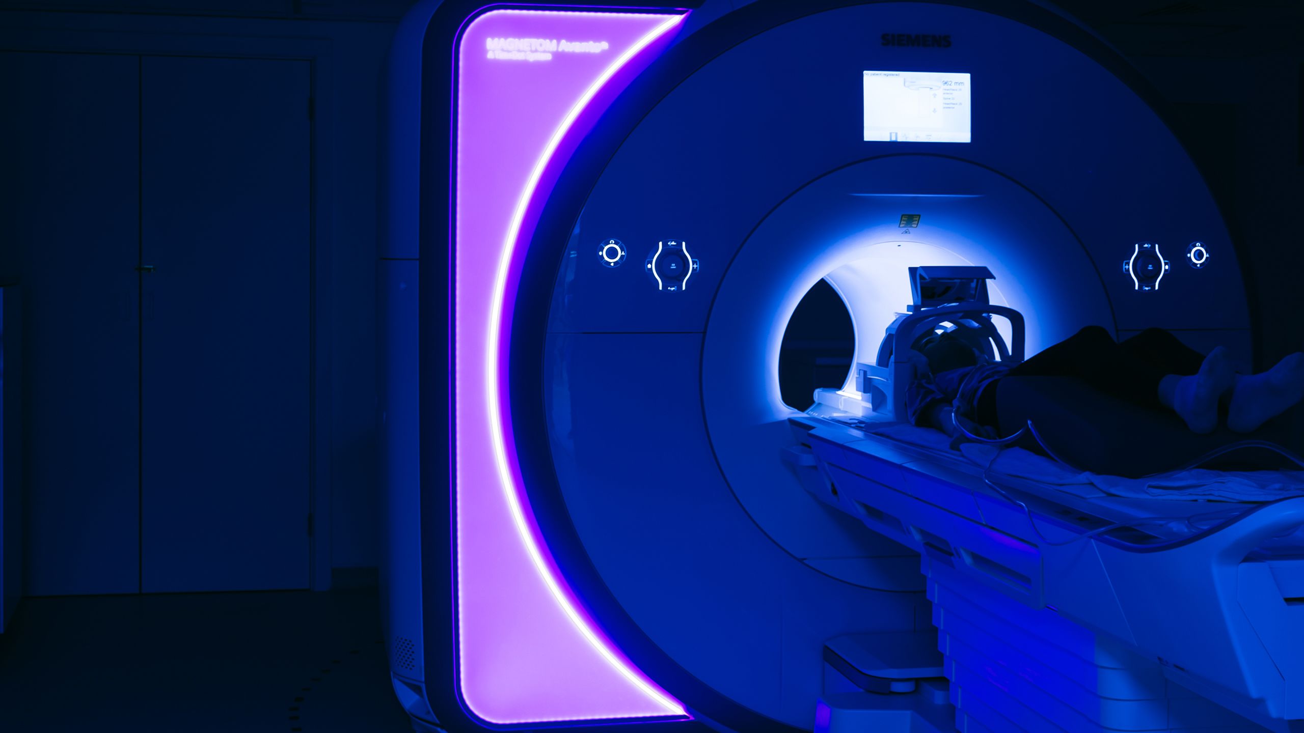 A girl lying inside a glowing blue MRI scanner.
